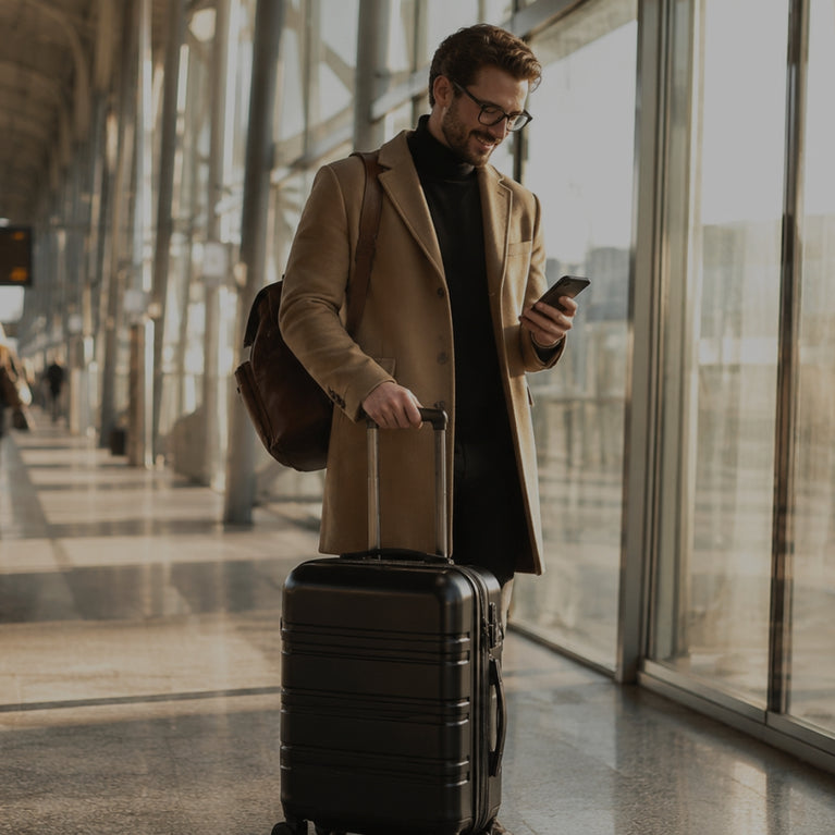 Man with suitcase and phone at an airport terminal