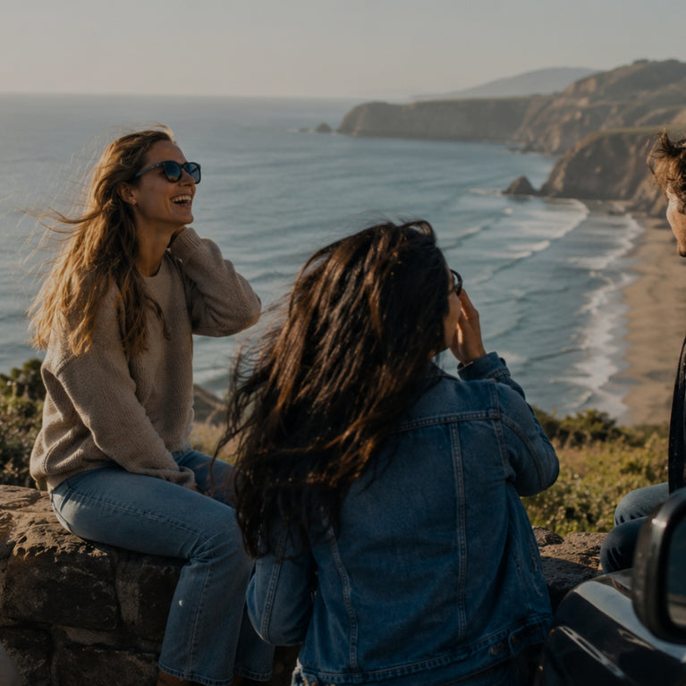 Four friends enjoying a scenic view by the ocean with a car in the foreground.